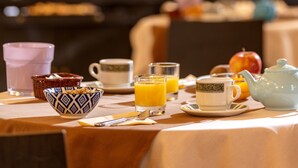 Una mesa de desayuno con diferentes alimentos para el desayuno, incluyendo una tetera, tazas y un bol.