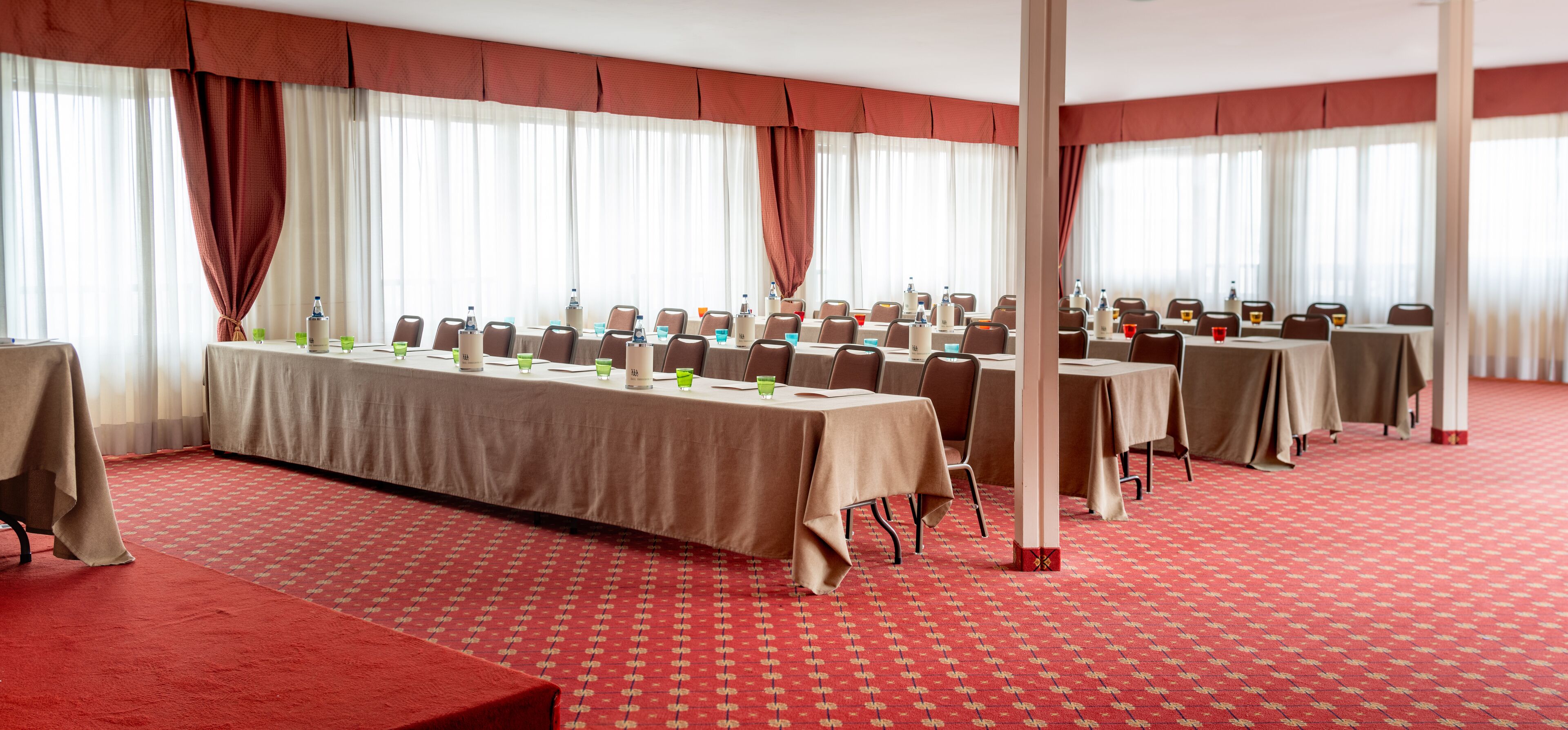 Ein Konferenzraum mit mehreren Tischen, Stühlen und Wasserflaschen.