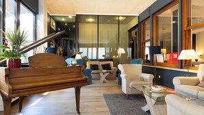 Una sala de estar moderna con un piano de cola, asientos cómodos y ventanas amplias.