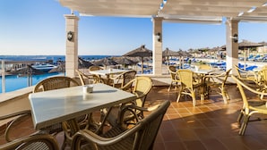Una terraza con mobiliario de mimbre, una piscina y vistas a la playa y al océano.