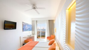 Habitación de hotel con cama, escritorio, silla, televisión y vistas al exterior.