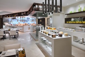 Un restaurant moderne doté d’un espace buffet, de tables et d’une cuisine visible au fond de la salle.