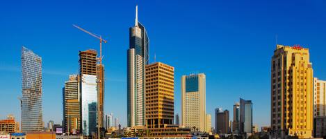 A cityscape with modern high-rise buildings, a highway, and palm trees.