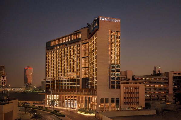 Un hôtel JW Marriott au design moderne, caractérisé par une enseigne bien visible sur le toit, de nombreux étages dotés de grandes fenêtres et une façade bien éclairée.