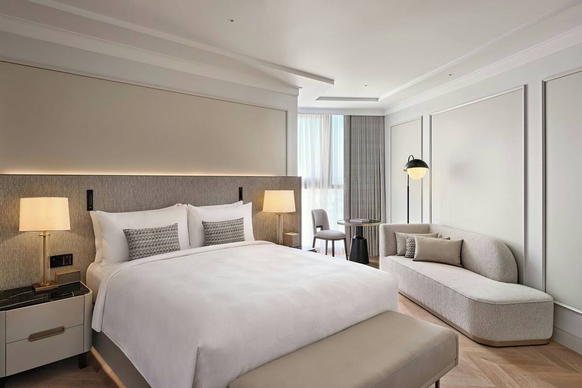Une chambre d’hôtel moderne avec un grand lit, des lampes de chevet, un canapé et une petite table.