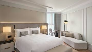 A modern hotel room with a large bed, bedside lamps, a sofa, and a small table.