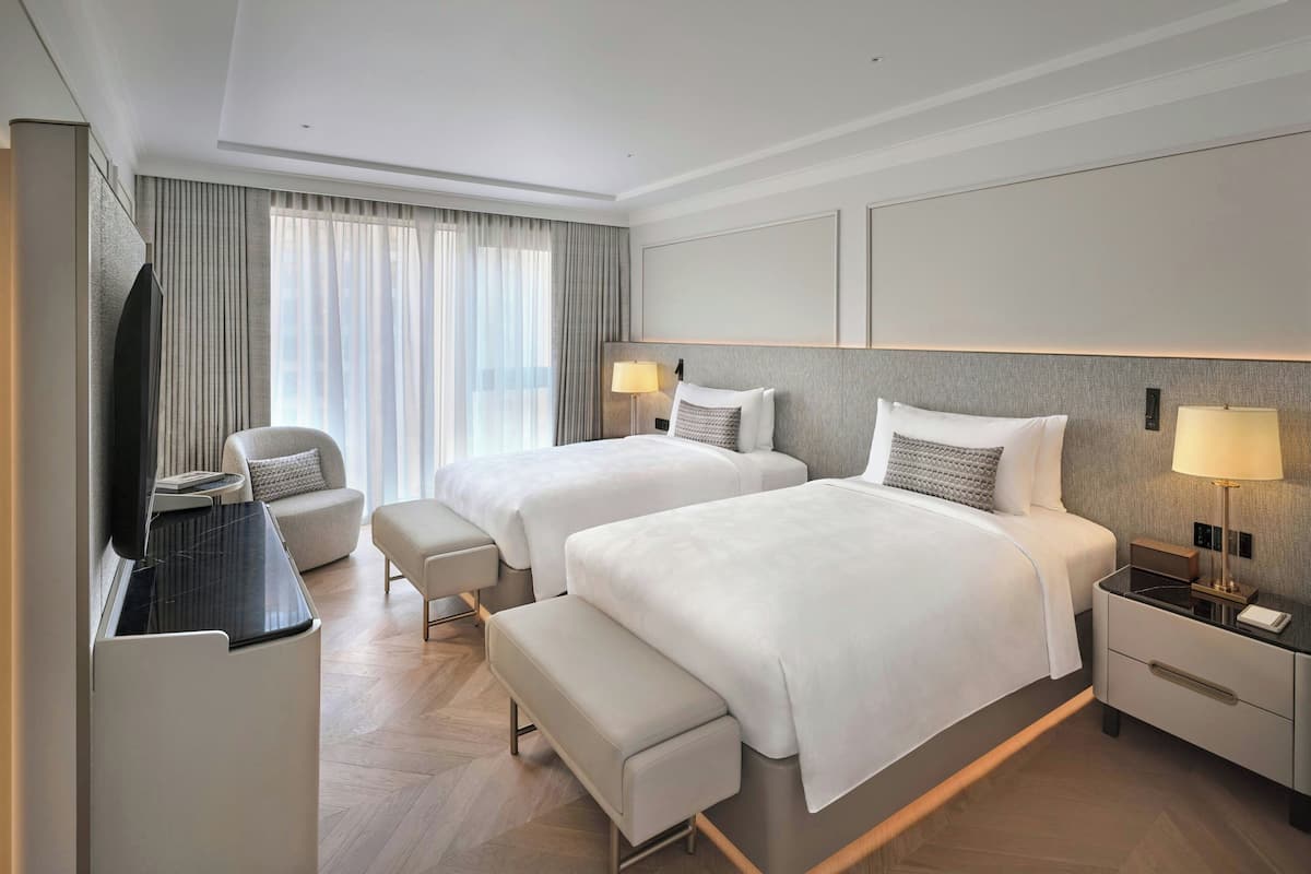 Une chambre d’hôtel avec deux lits, une télévision, un bureau et une chaise.