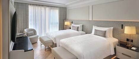 Habitación de hotel con dos camas, televisor, escritorio y silla.
