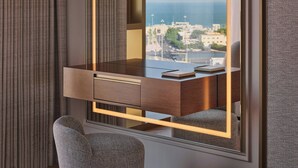 Ein modernes Hotelzimmer mit einem Holztisch, einem Stuhl und einem großen Fenster mit Blick auf die Stadt.