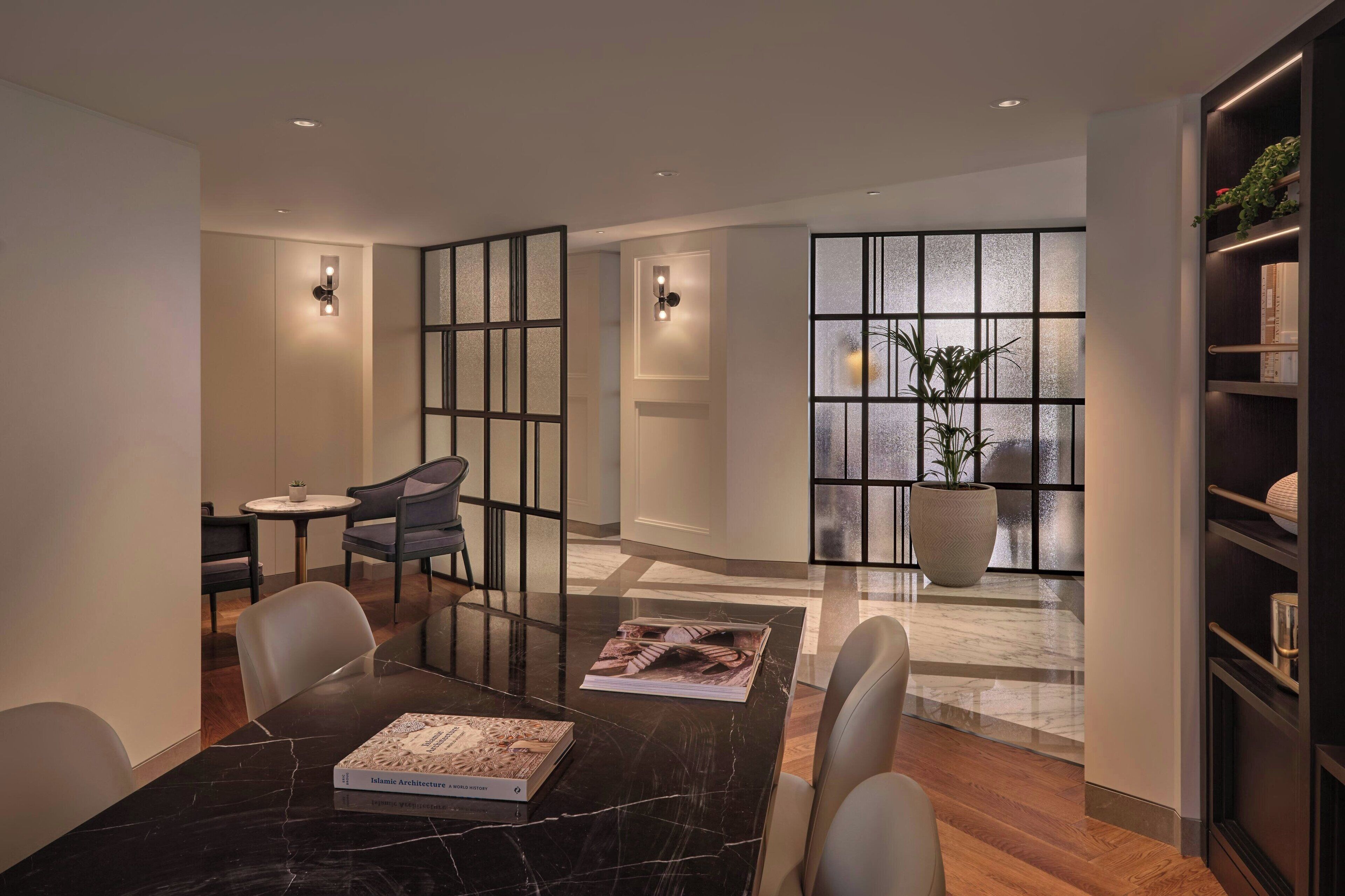 A modern interior with a dining table, chairs, a potted plant, and a bookshelf.