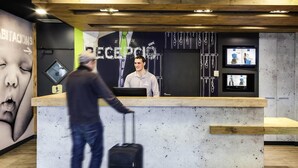 Un taulell de recepció de fusta, una pantalla digital i una paret amb un cartell gran.