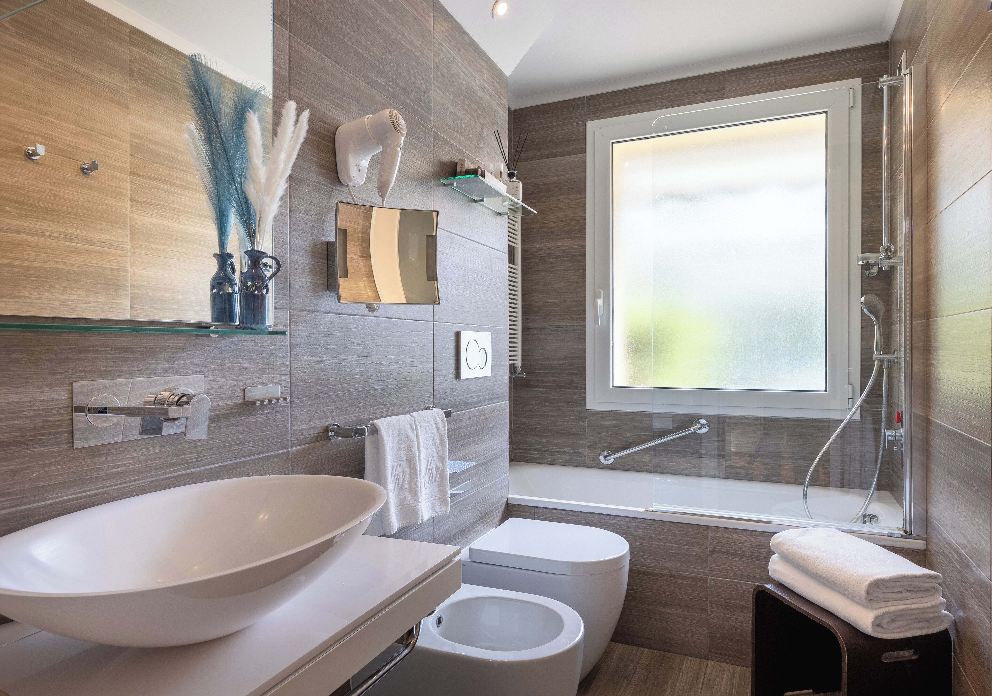 A modern bathroom with a large oval sink, a toilet, a bathtub, and a shower.