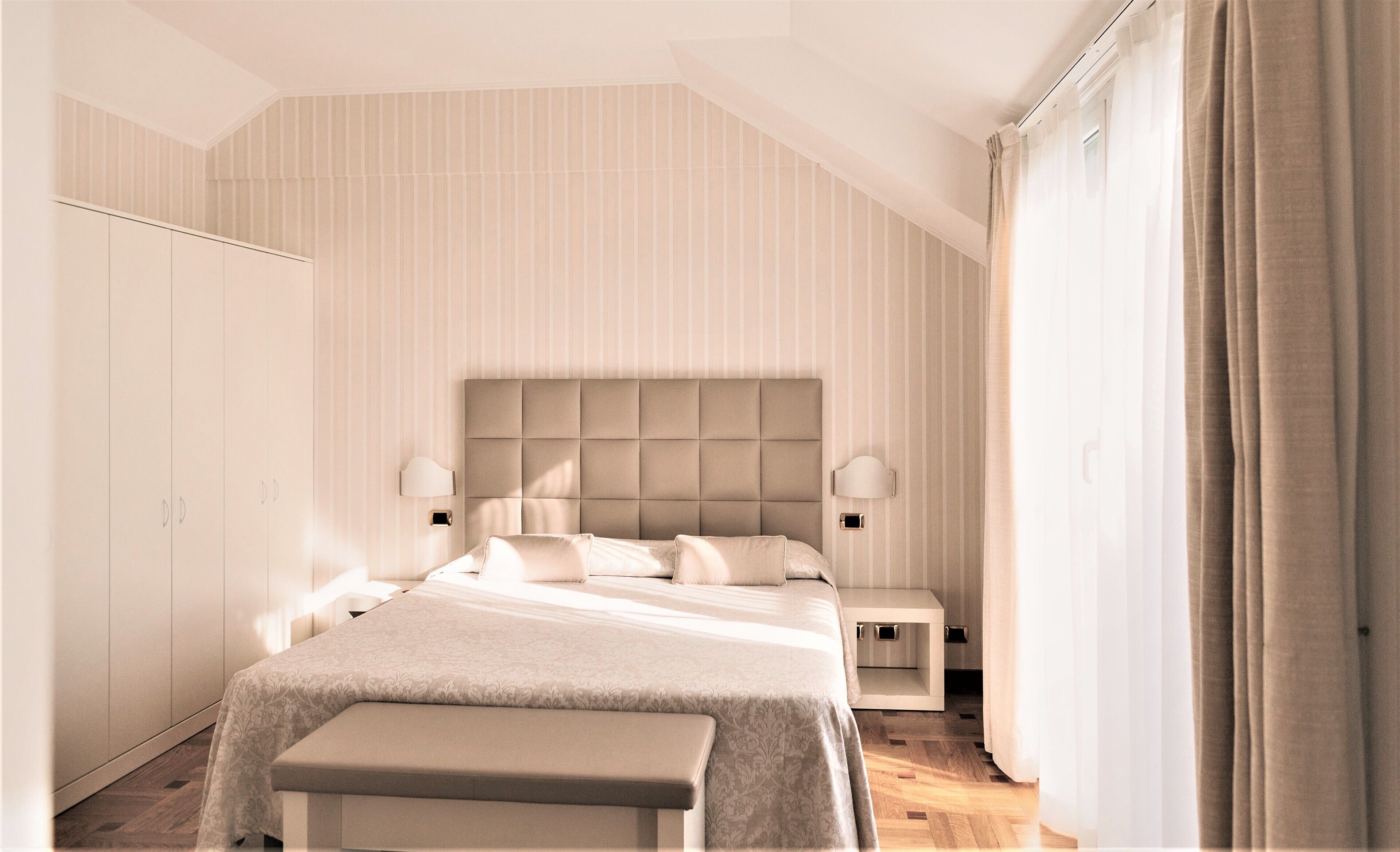 Un dormitorio moderno con una cama grande, mesitas de noche y un armario.