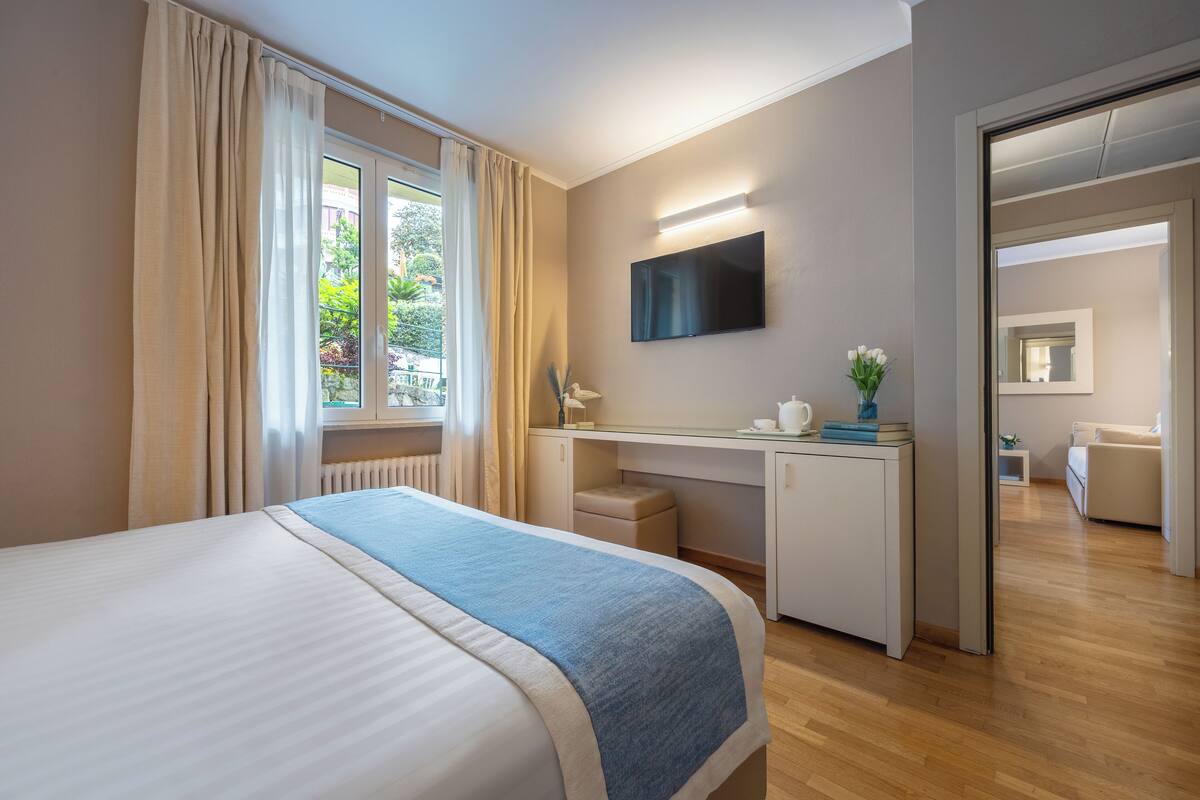 Une chambre d’hôtel moderne dotée d’un grand lit, d’un bureau, d’une télévision à écran plat et offrant une vue sur l’extérieur.