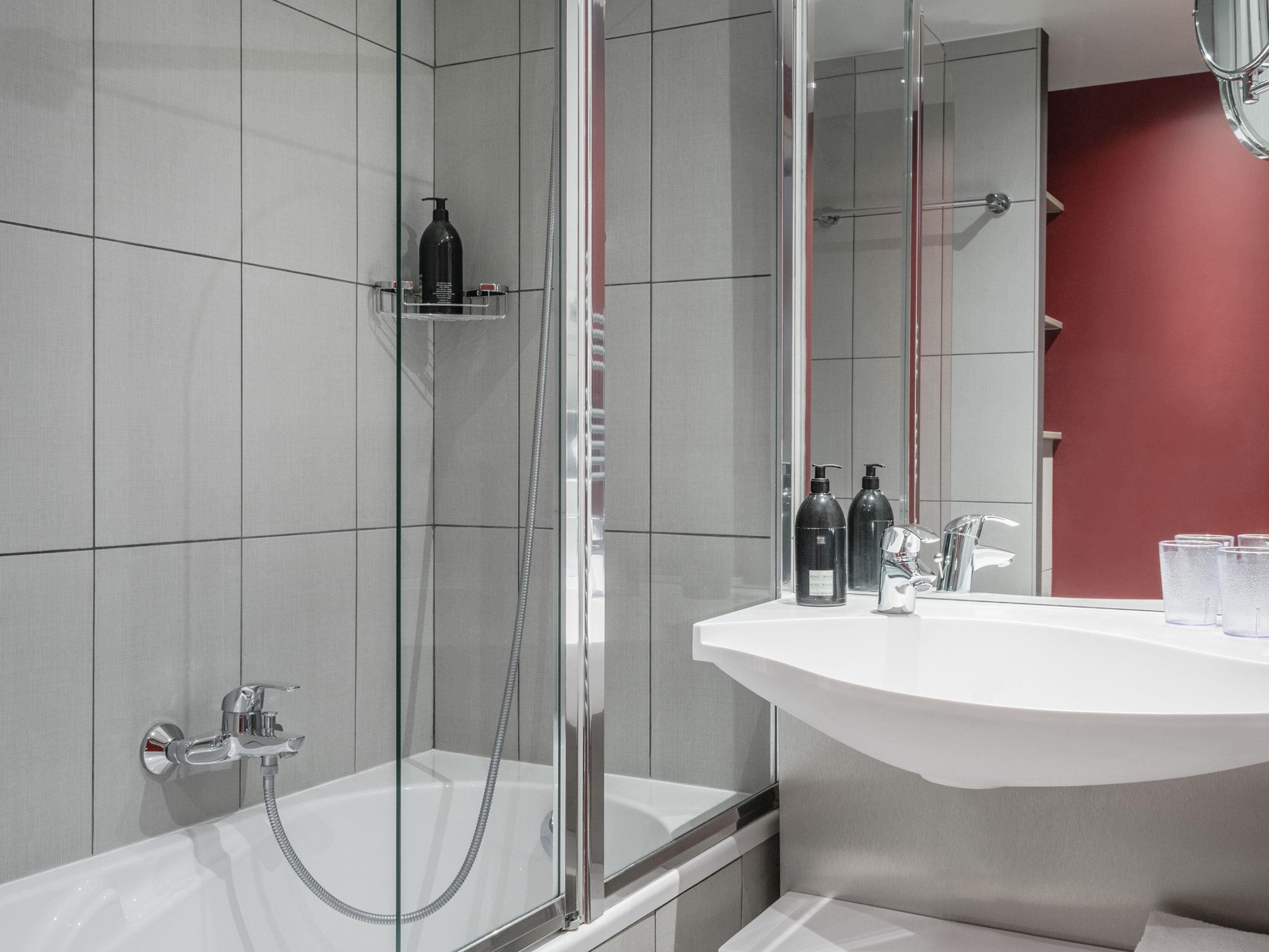 A modern bathroom with a glass-enclosed shower, a white sink, and a mirror.