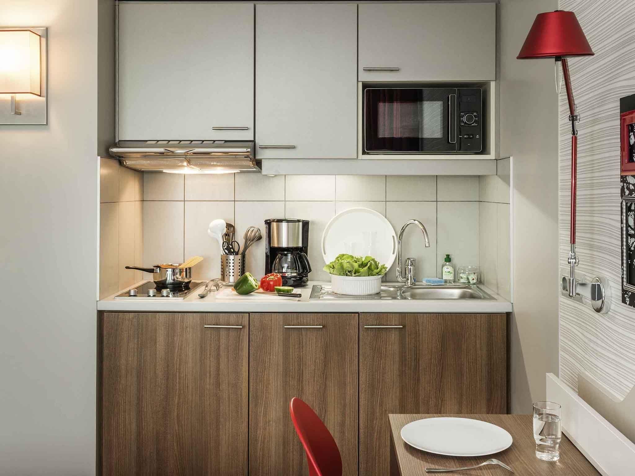 A compact kitchen with a microwave, coffee maker, and a sink.