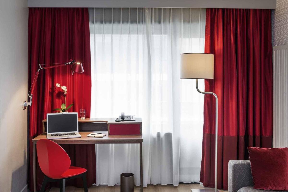 Een hotelkamer met een bureau, een stoel, een lamp en een bank.