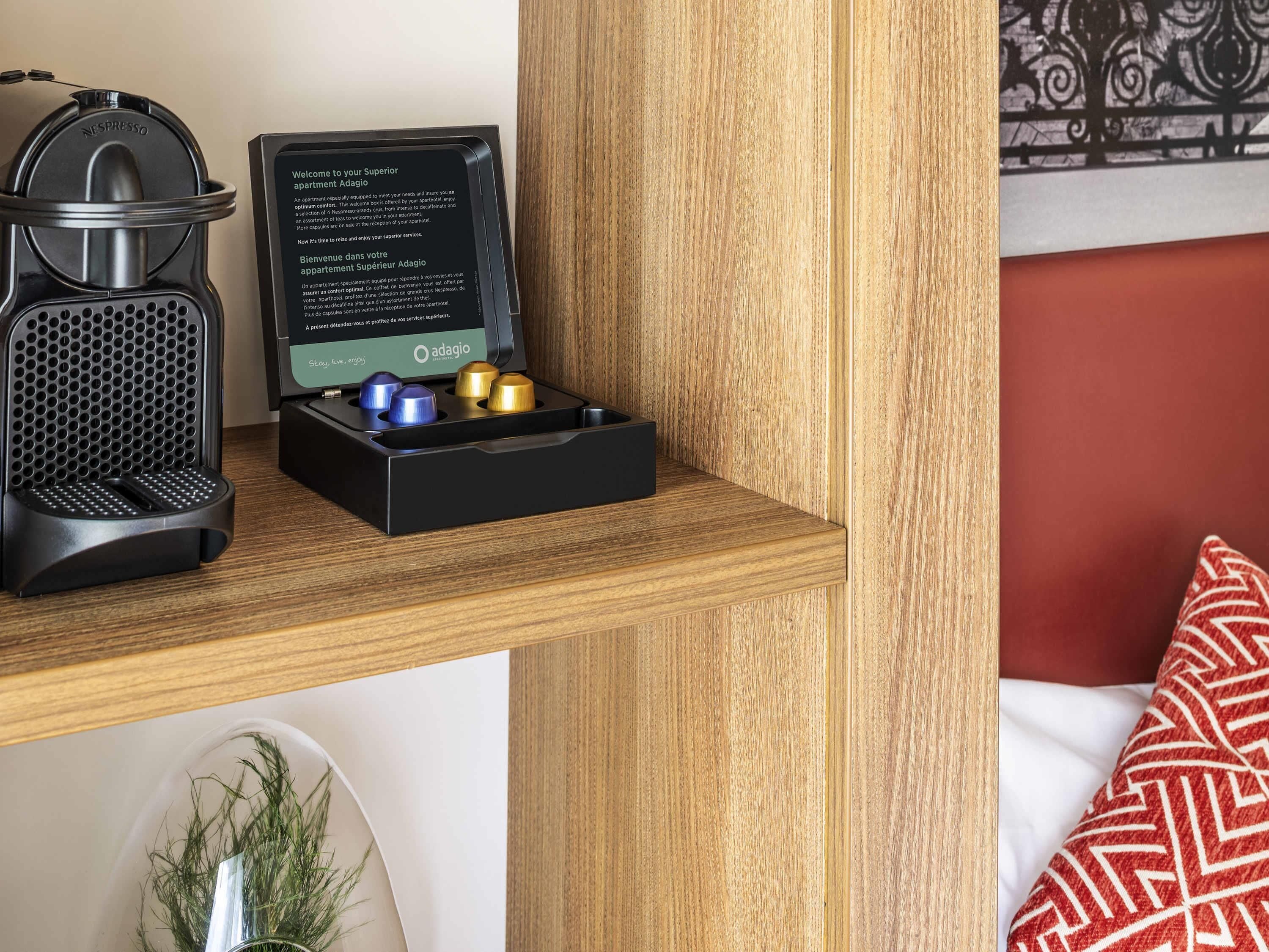 Una máquina de café Nespresso, una caja negra con pantalla digital y un compartimento para cuatro cápsulas.
