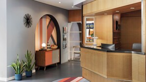 A modern reception area with a wooden reception desk, a large decorative wall, and potted plants. - Hotel La Pergola (Bern)