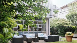 An outdoor seating area with wicker furniture and a potted plant. - Hotel La Pergola (Bern)
