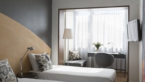 A hotel room with two beds, a desk, a chair, a lamp, and a TV. - Hotel La Pergola (Bern)