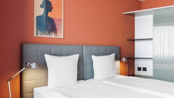 Une chambre d’hôtel avec un lit, une table de chevet, une lampe, un tableau au mur et une porte coulissante de placard.