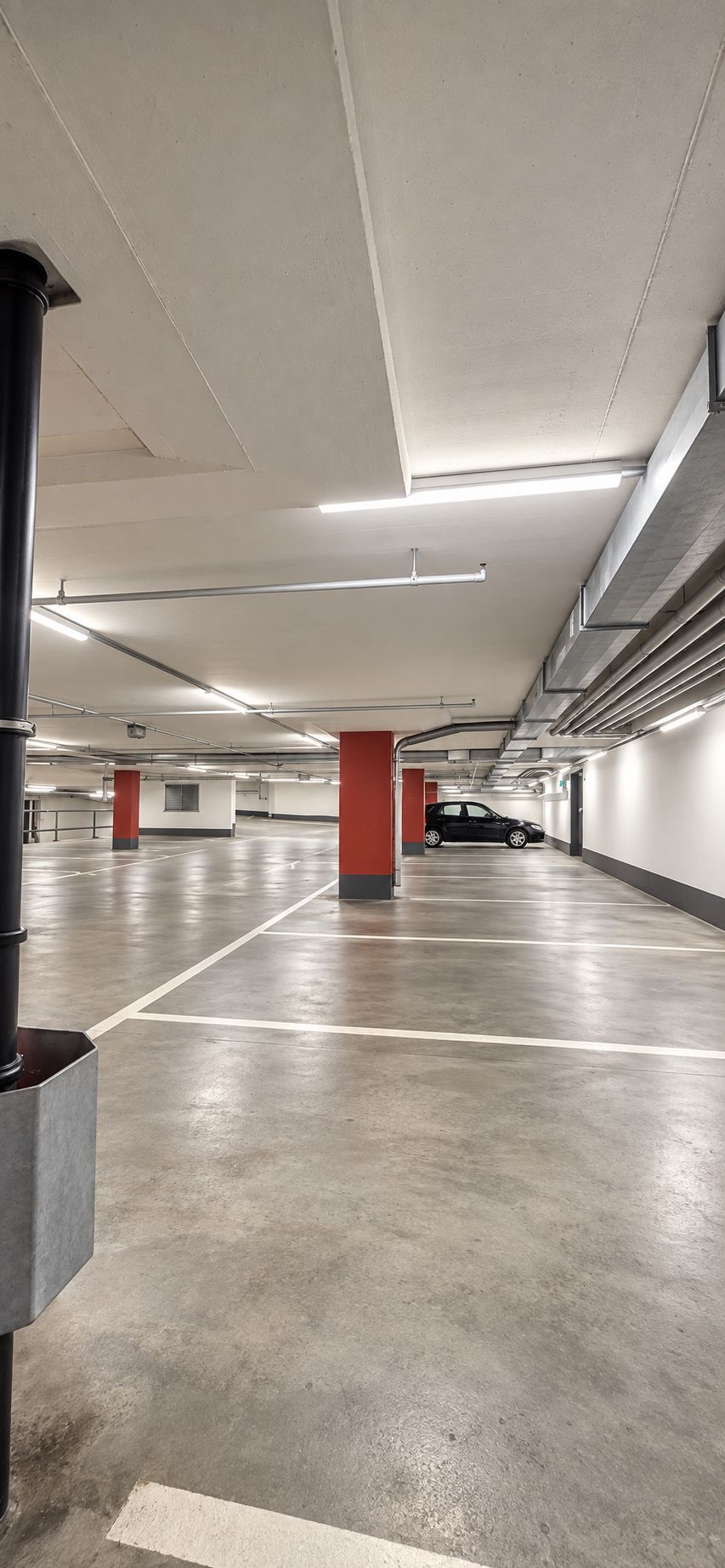 A parking garage with multiple levels, concrete floors, and overhead lighting.