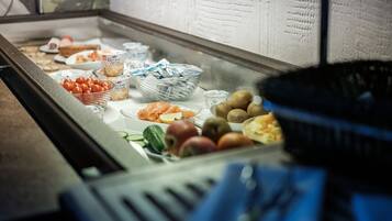 Un buffet proposant une variété d’aliments, notamment des fruits, des légumes et de la charcuterie.