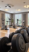 Un gimnasio con diversos equipos de ejercicio, incluyendo cintas de correr y mancuernas.
