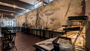 A restaurant with wooden flooring, a buffet counter, and a mural of trees and flowers on the wall.