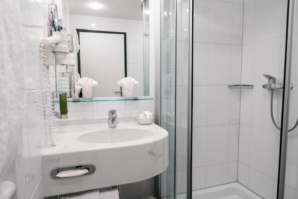 Une salle de bain moderne avec une douche à parois de verre, un lavabo blanc et un miroir.