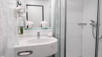 Une salle de bain moderne avec une douche à parois de verre, un lavabo blanc et un miroir.
