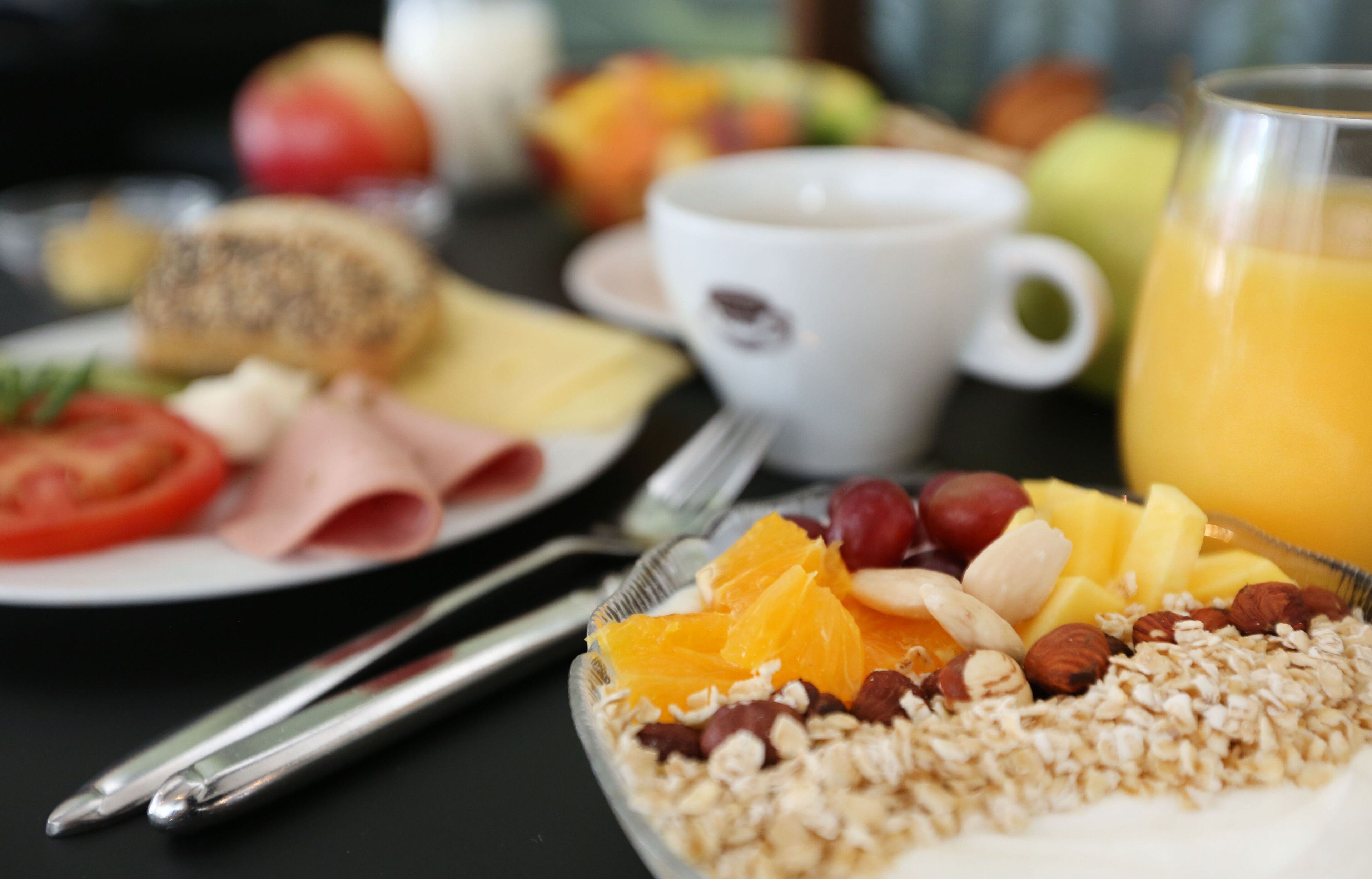 A breakfast setting with plates of food, a cup of coffee, and a glass of orange juice.