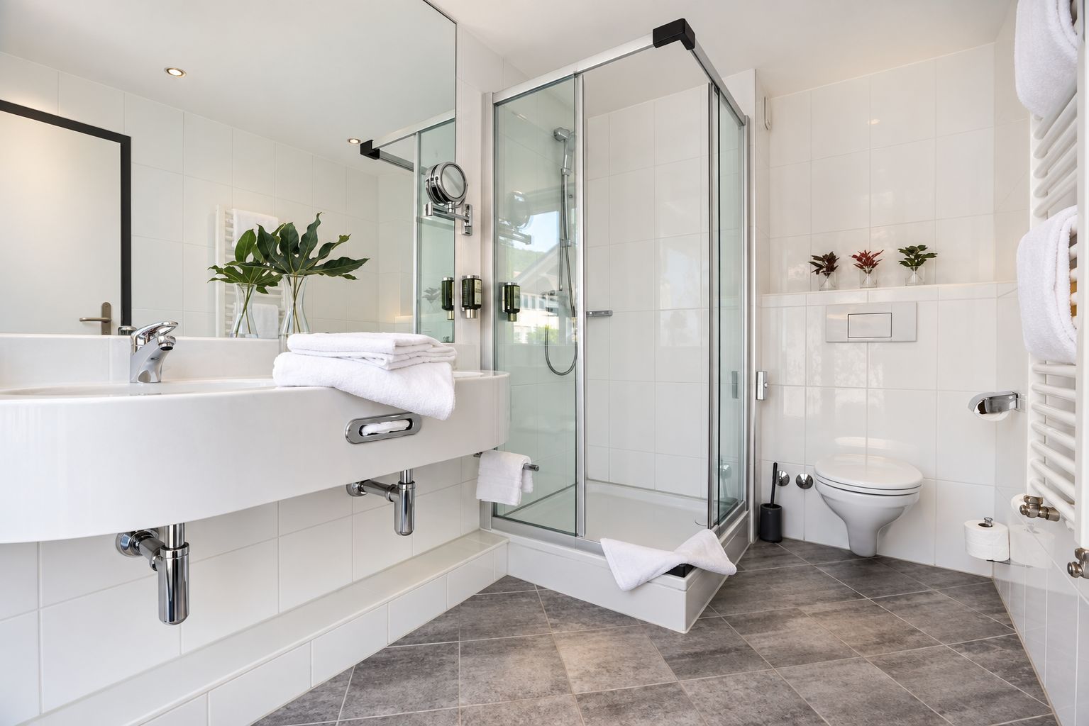 A modern bathroom with a glass-enclosed shower, a large white sink, and a toilet.