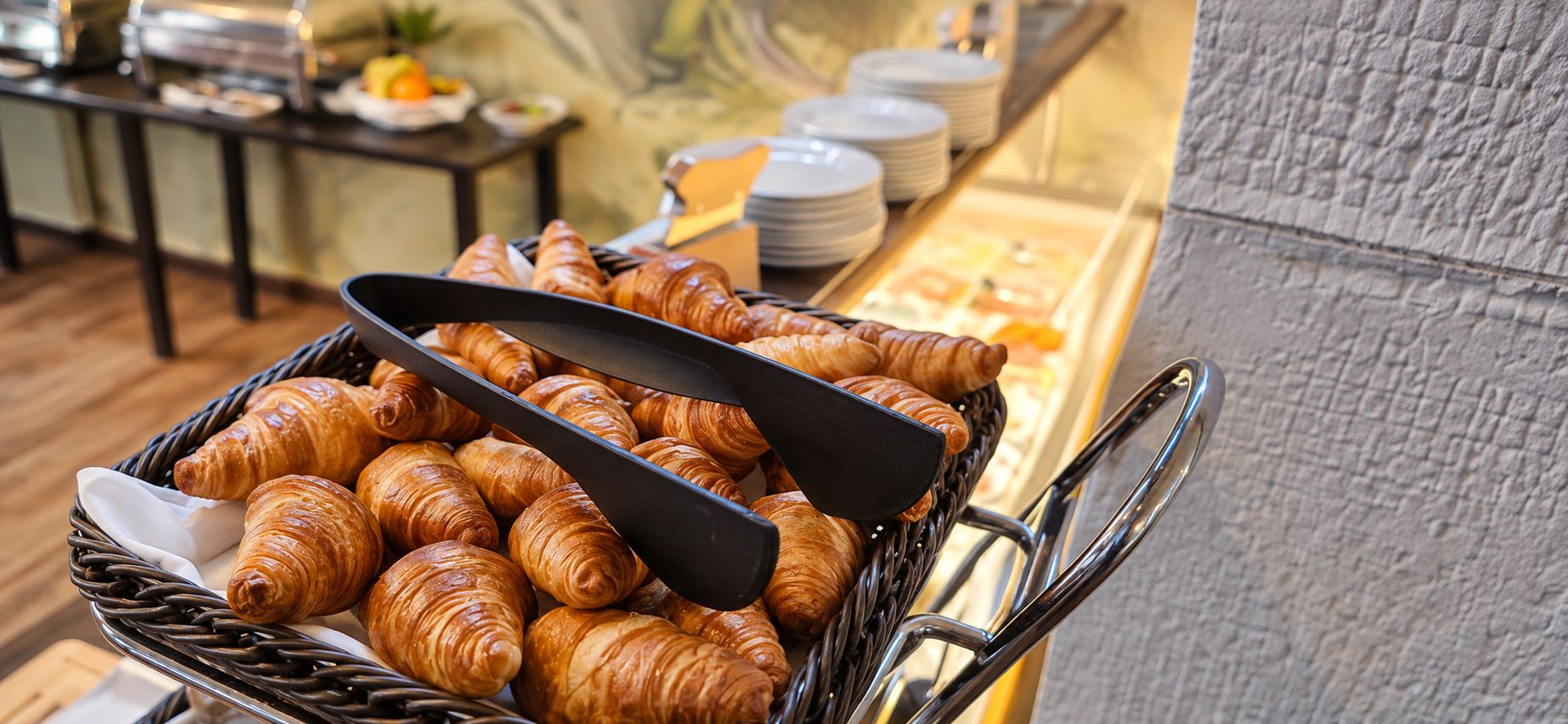 A buffet cart filled with croissants and a black spatula.