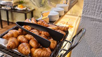 A buffet cart filled with croissants and a black spatula.