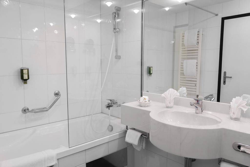 Une salle de bain moderne avec une douche à parois de verre, un lavabo blanc et un grand miroir.