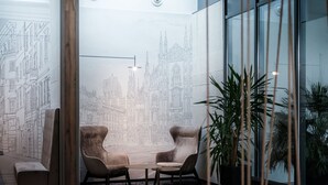 Un vestíbulo moderno con un gran mural en la pared, dos sillones, una mesita y una planta en maceta.