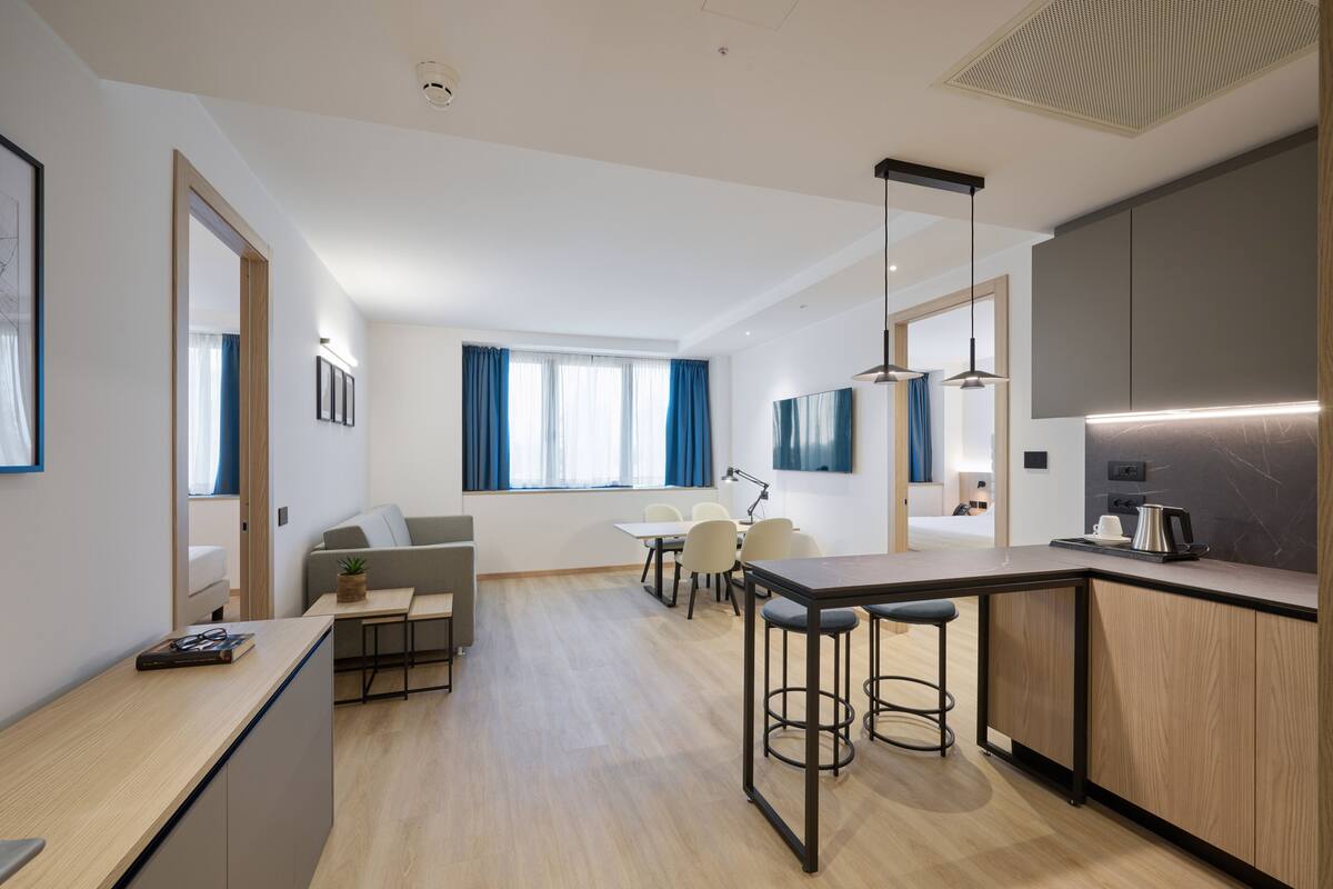 Una cocina moderna con barra, una mesa de comedor con sillas y un sofá en la sala de estar.