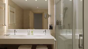 A modern bathroom with a large sink, mirror, and glass shower enclosure.