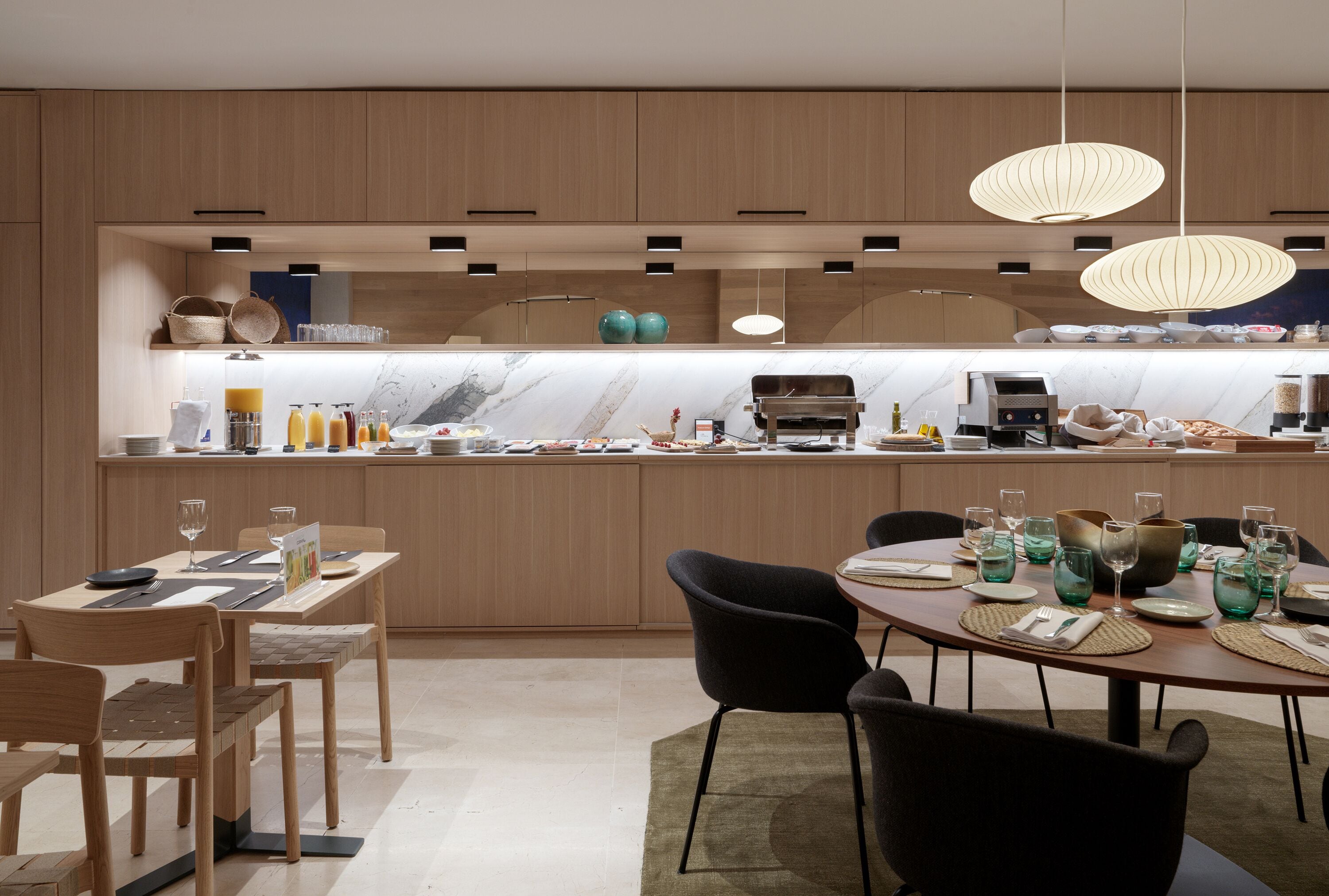 Una cocina moderna con armarios de madera, encimera de mármol e iluminación colgante.