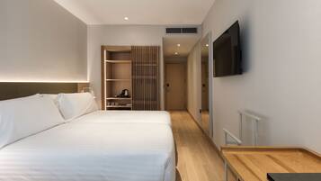 Una habitación de hotel moderna con una cama grande, un escritorio de madera y un televisor montado en la pared.