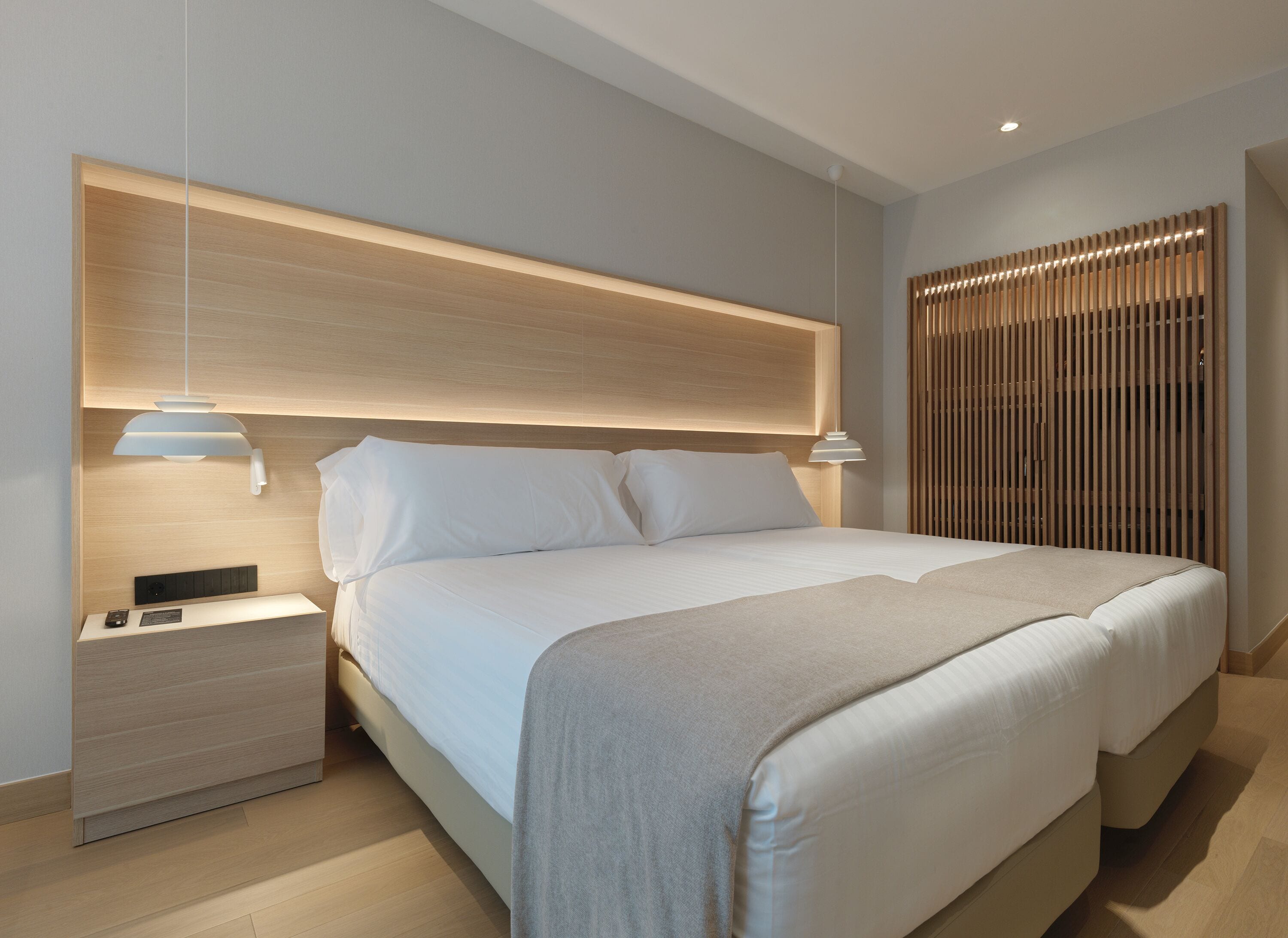 A modern bedroom with a large bed, bedside tables, and a wooden headboard.