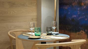 Una mesa de comedor redonda con cuatro sillas de madera, una lámpara y tres copas de vino.