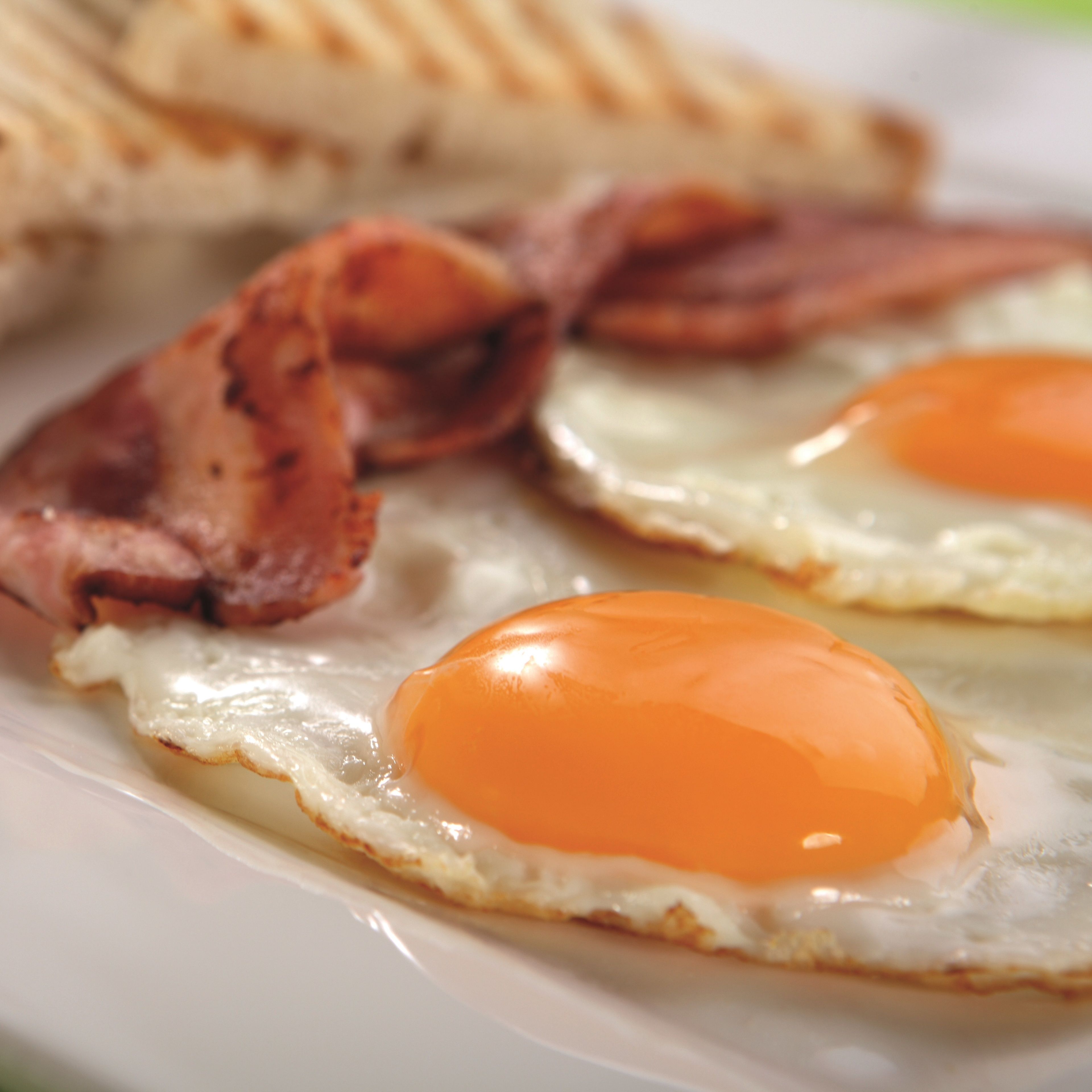 A breakfast plate with two fried eggs and bacon strips.