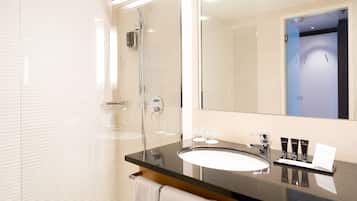 A modern bathroom with a glass-enclosed shower, a large mirror, and a black countertop with a white sink.