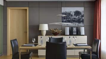 A modern dining area with a wooden table, black chairs, a white lamp, and a black and white cityscape artwork on the wall.