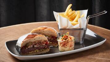 A sandwich cut in half, a small container of fries, and a small bowl of salad on a plate.