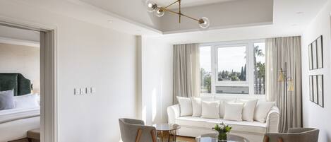 A modern living room with a white sofa, two armchairs, a coffee table, and a chandelier.