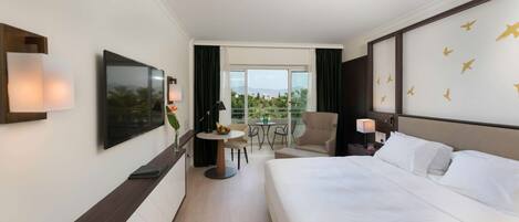 Una habitación de hotel con cama, escritorio con silla, televisión y balcón con vistas.